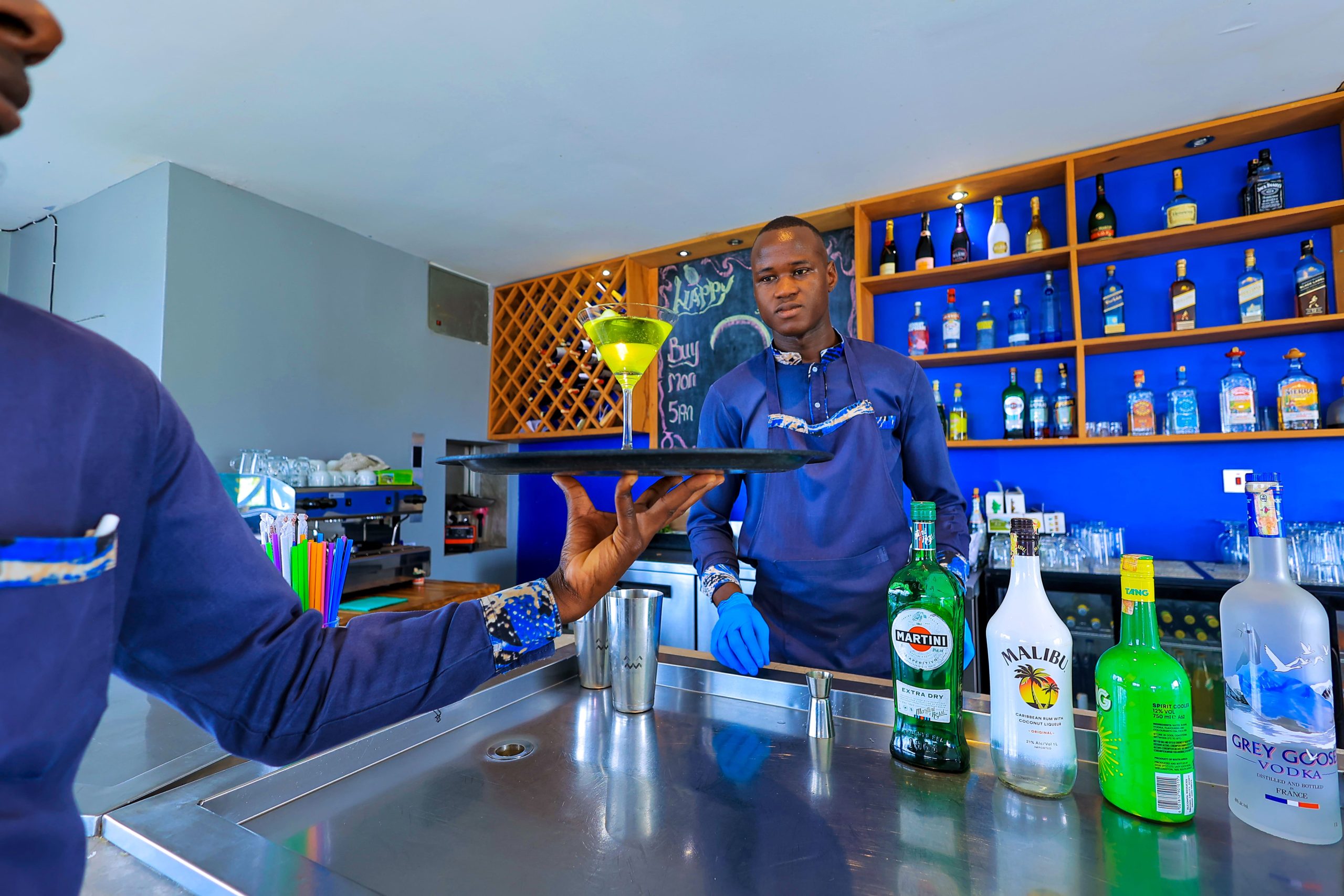Bar area at Aquarius Kigo Resort with shelves of bottles and a person standing nearby.